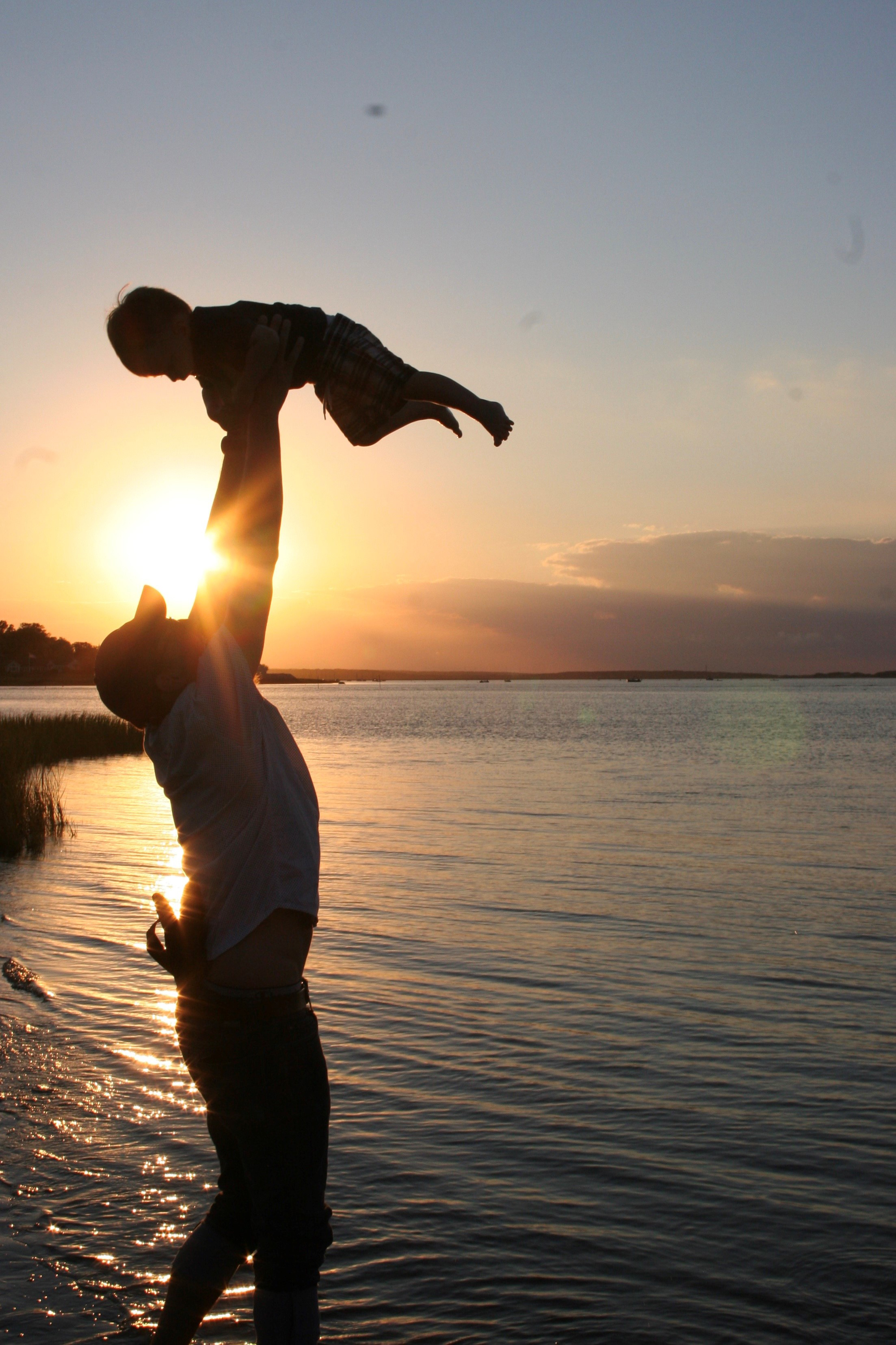 Dad holds son up in the air by the shore
